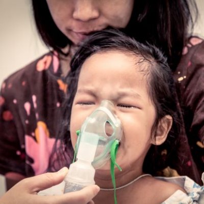 Woman holding inhaler mask to child's face. Image, Adobe.